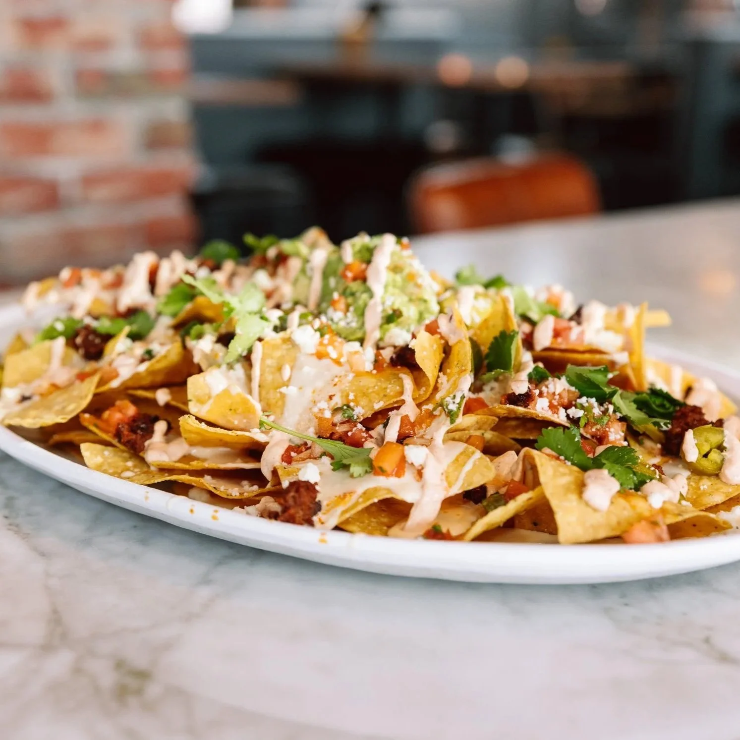 Close-up of loaded nachos on a bar table at The goat.