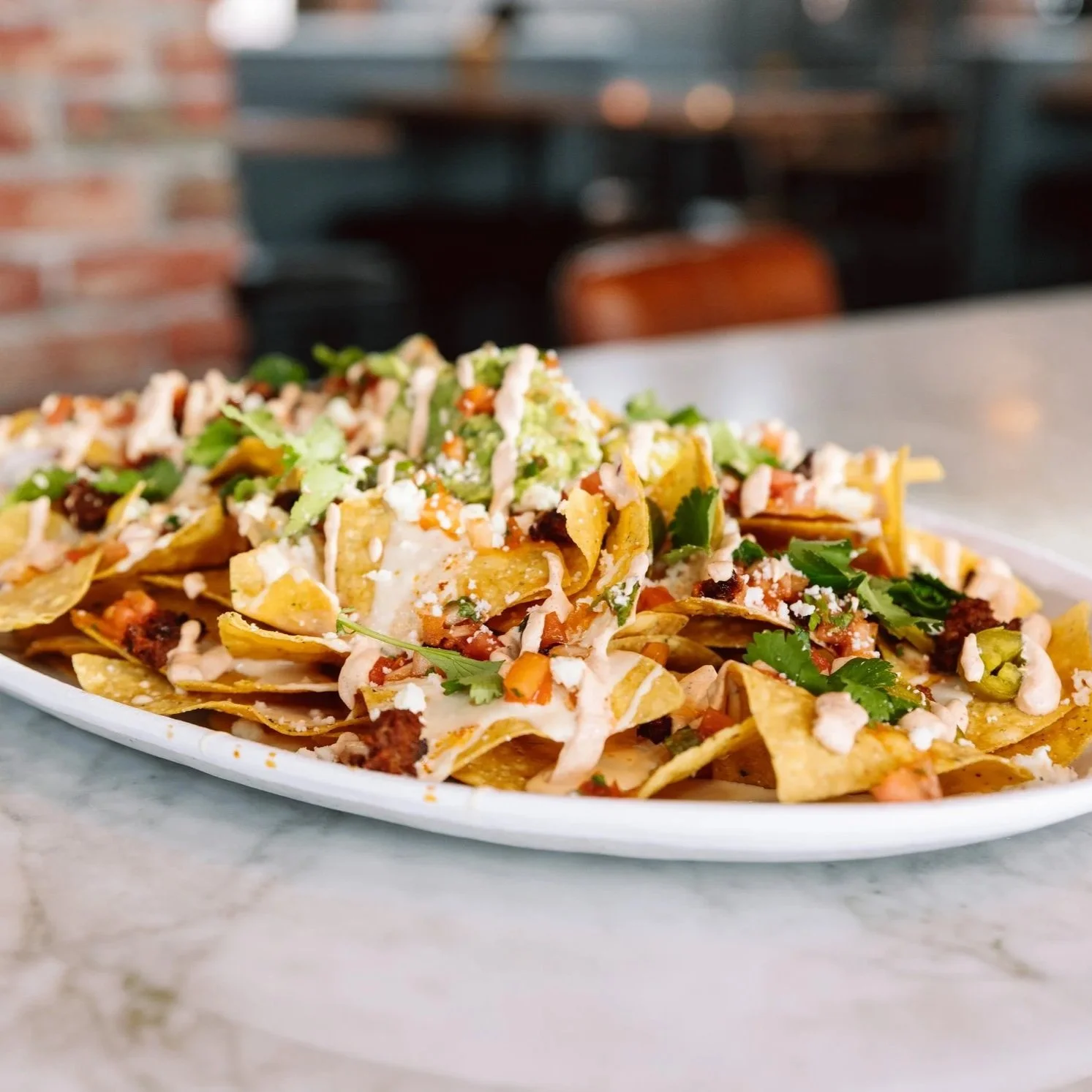 Close-up of loaded nachos on a bar table at The goat.