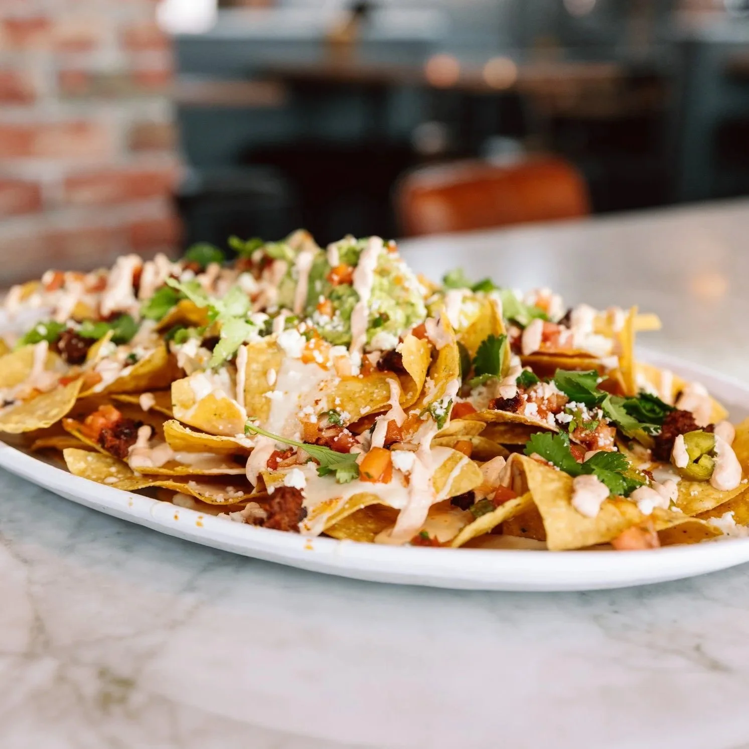 Close-up of loaded nachos on a bar table at The goat.