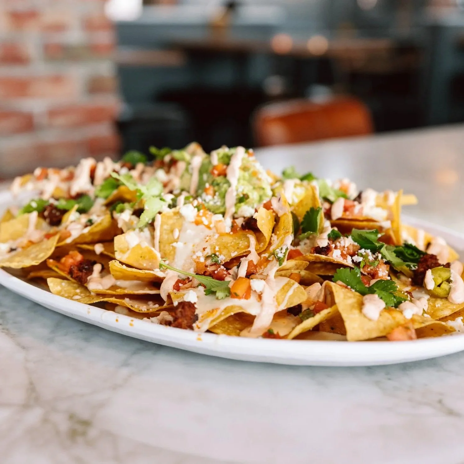 Close-up of loaded nachos on a bar table at The goat.