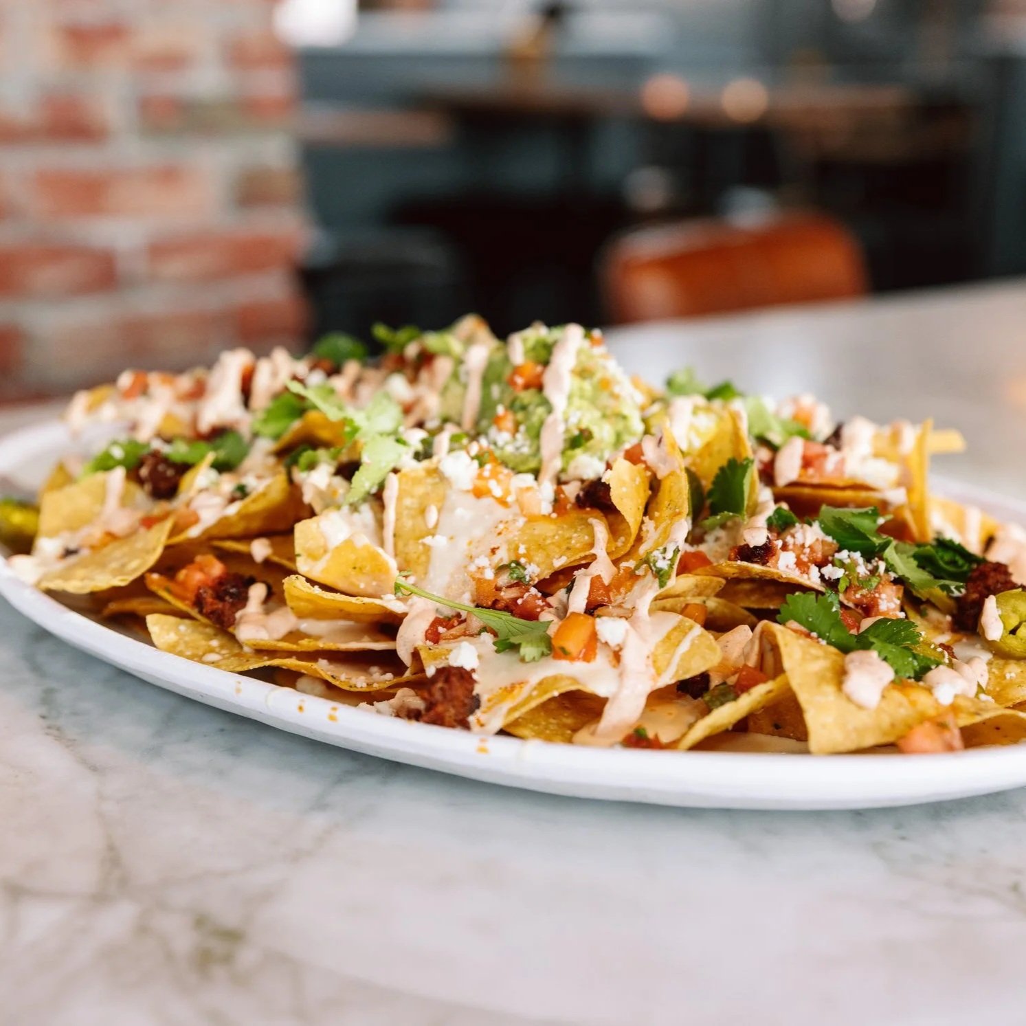 Close-up of loaded nachos on a bar table at The goat.