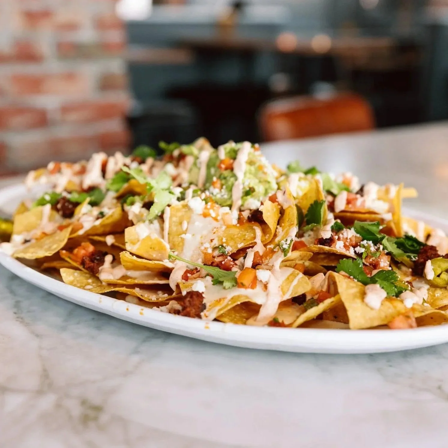 Close-up of loaded nachos on a bar table at The goat.