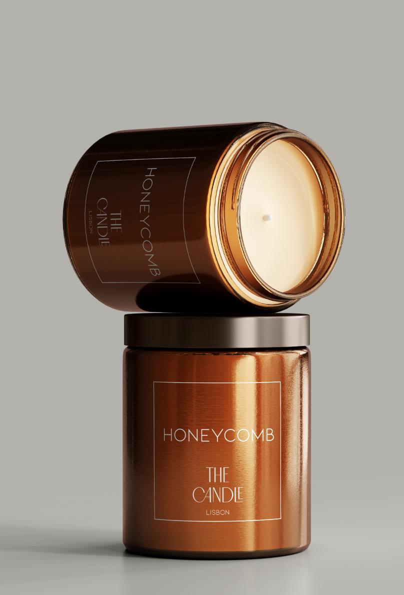 A glossy amber-colored candle jar labeled 'HONEYCOMB THE CANDLE LISBON', with the lid placed on top, revealing an unlit white candle inside.