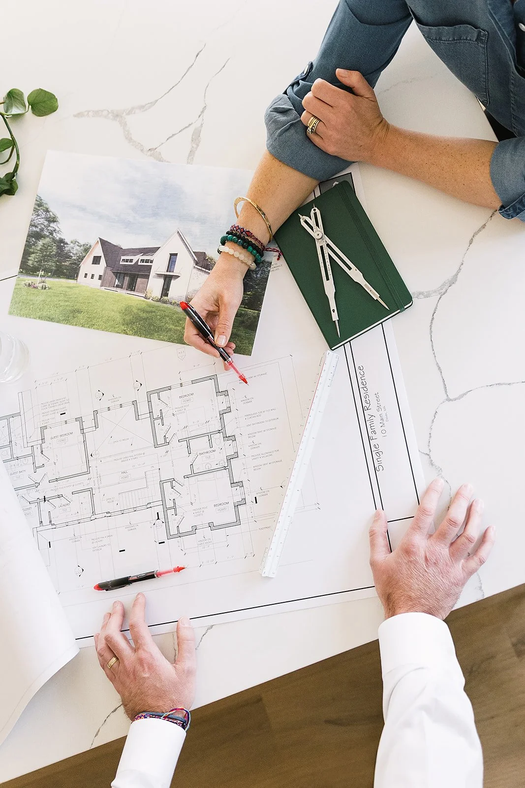 Architectural blueprint of a house with a photograph of a modern house on a table.
