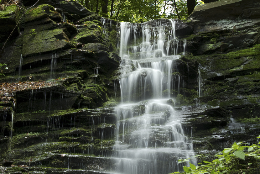 Waterfall cascading over moss-covered rocks in a lush green forest