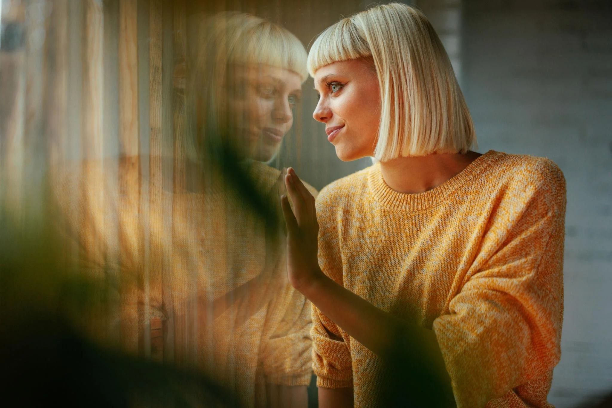Pensive person looking out window at home