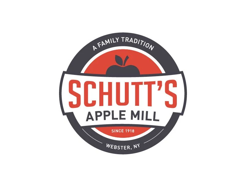 Logo for Schutt's Apple Mill with a red and black color scheme, including an apple graphic and text indicating the family tradition since 1918 in Webster, NY.