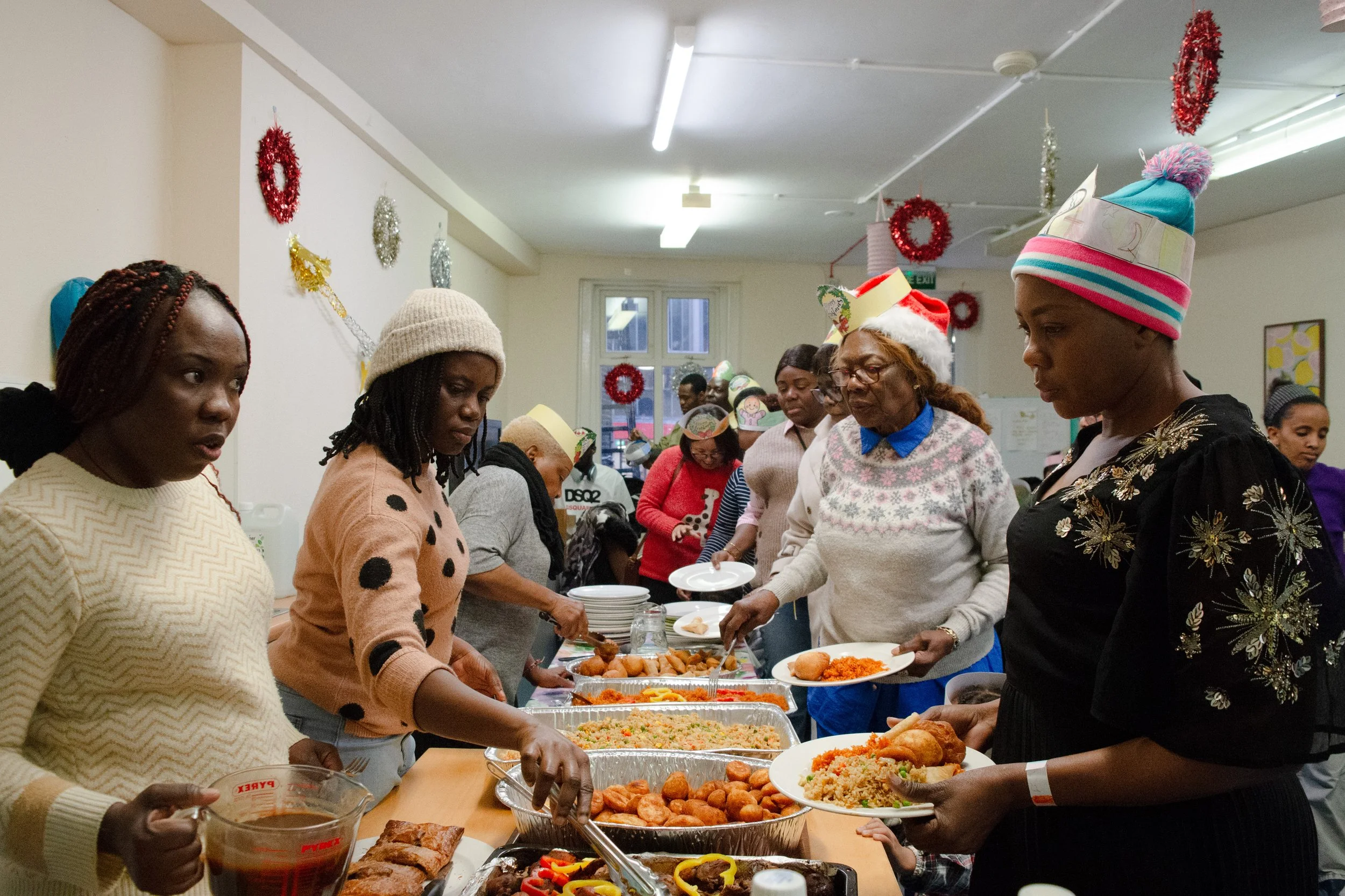 People gathered around a table with Christmas decorations, serving and eating holiday food in a festive indoor setting.