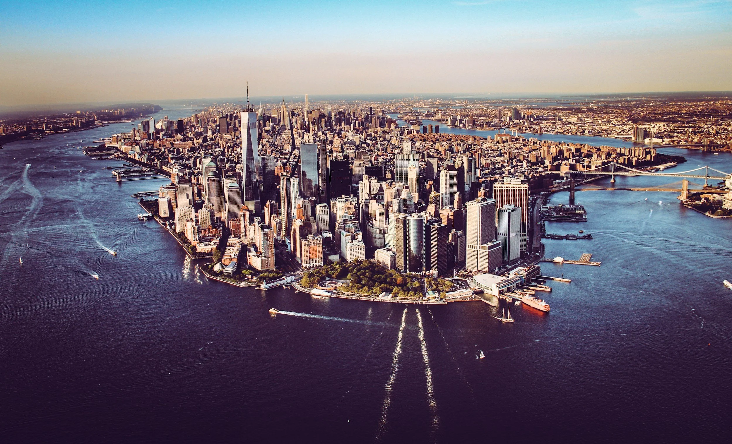 Aerial view of Manhattan, New York City with skyscrapers, water, and bridges.
