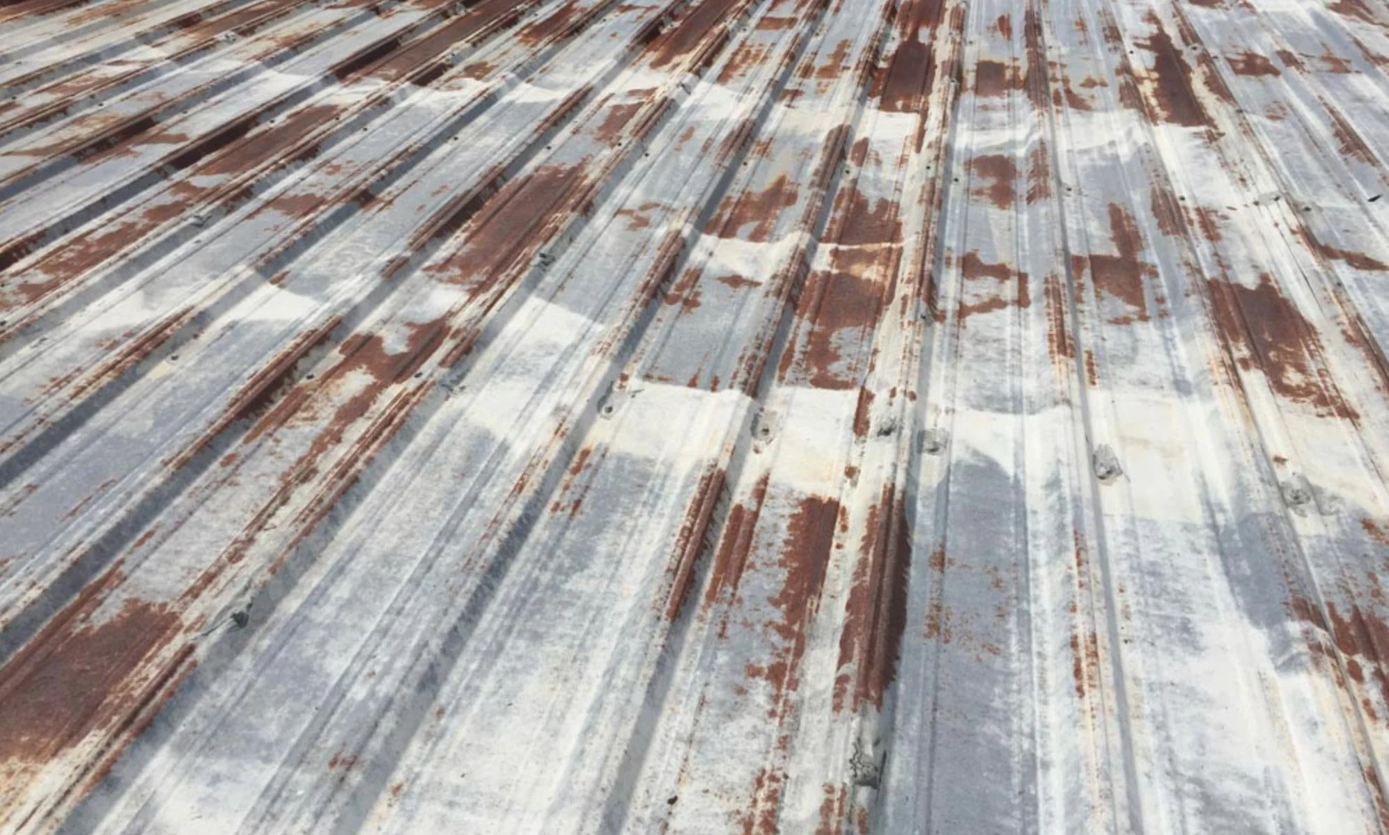 Rusty metal roof with peeling paint and weathered texture.