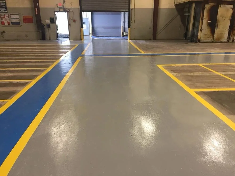 View of an empty indoor parking garage with freshly painted yellow and blue lines designating parking spaces and walkways.