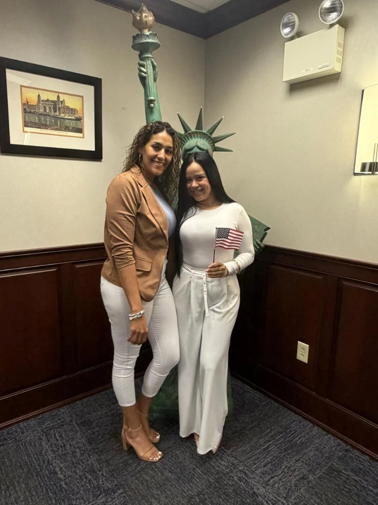 Two women standing in an office while one holds a small USA flag.