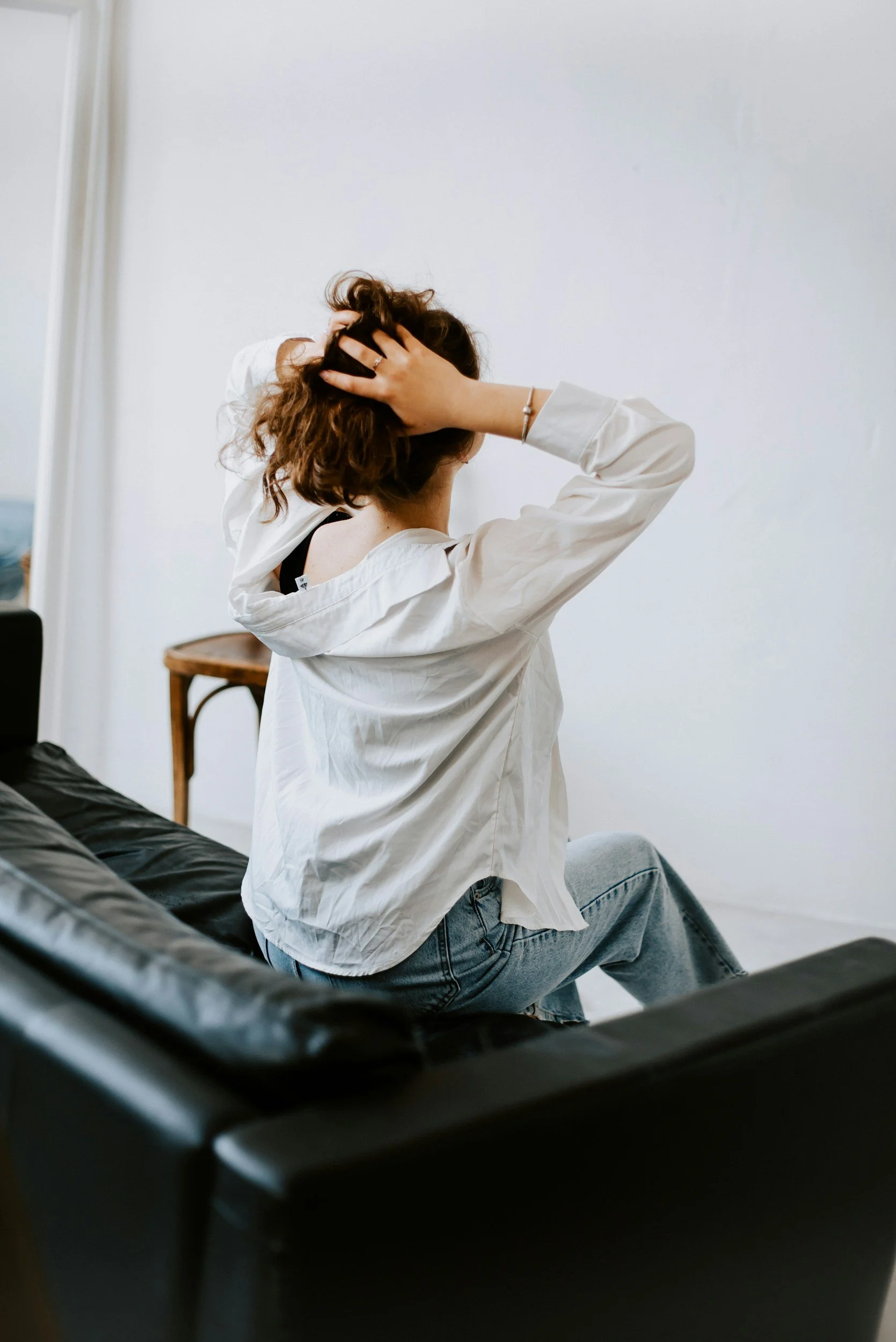 woman sitting on a couch thinking and holding her head