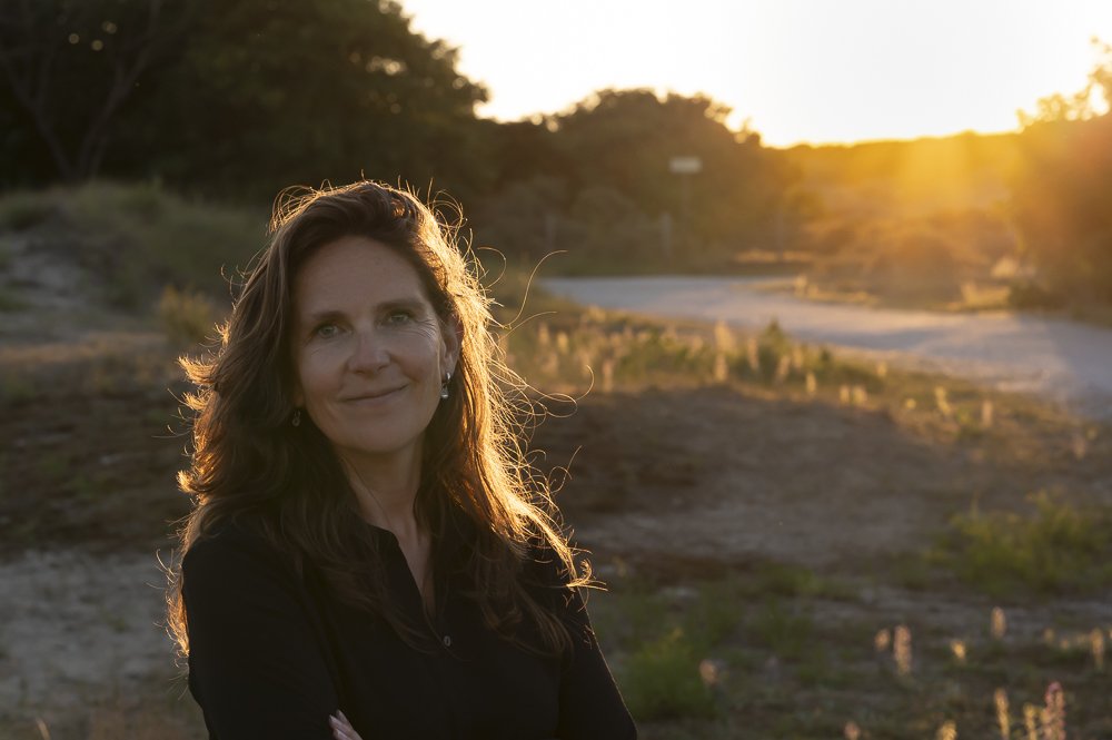 Een vrouw met bruin haar die tijdens zonsondergang buiten staat.