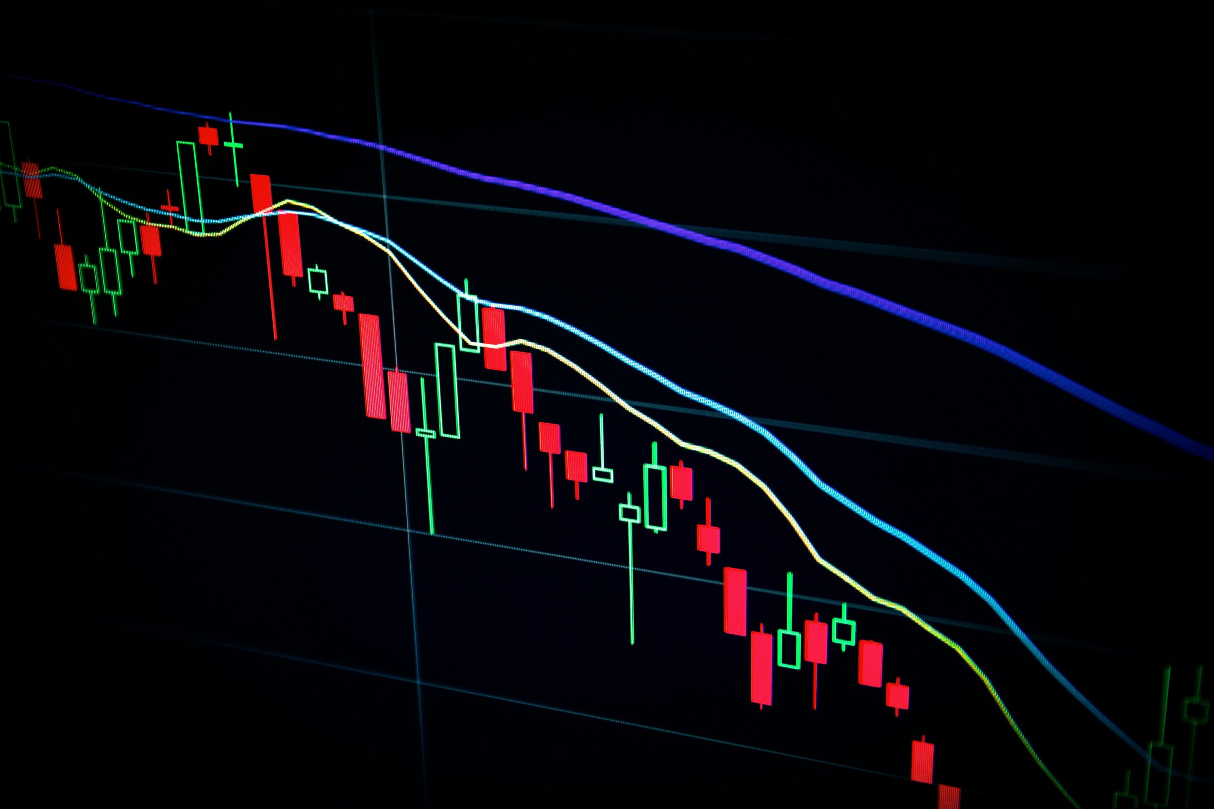Digital stock market chart with red and green candlesticks and multiple moving average lines on a dark background.