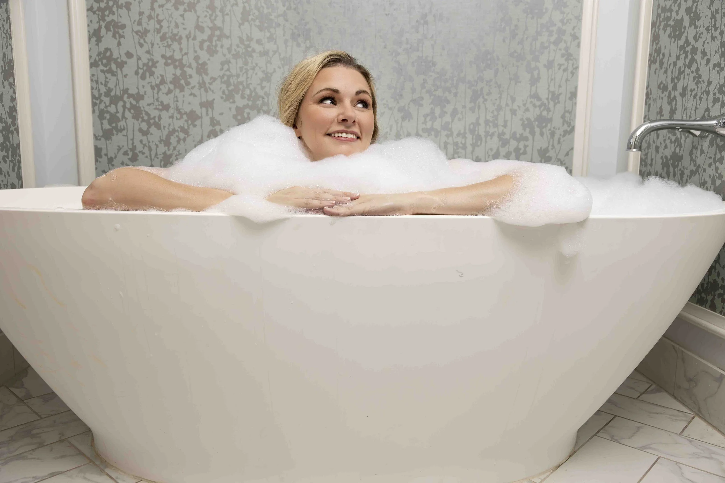 Woman relaxing in a bubble bath with a smile.
