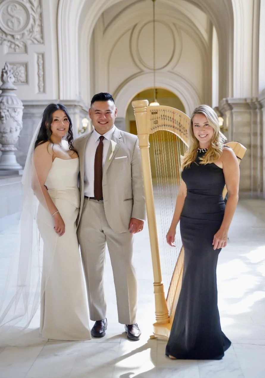 A wedding harpist next to a couple at their wedding at San Francisco City Hall