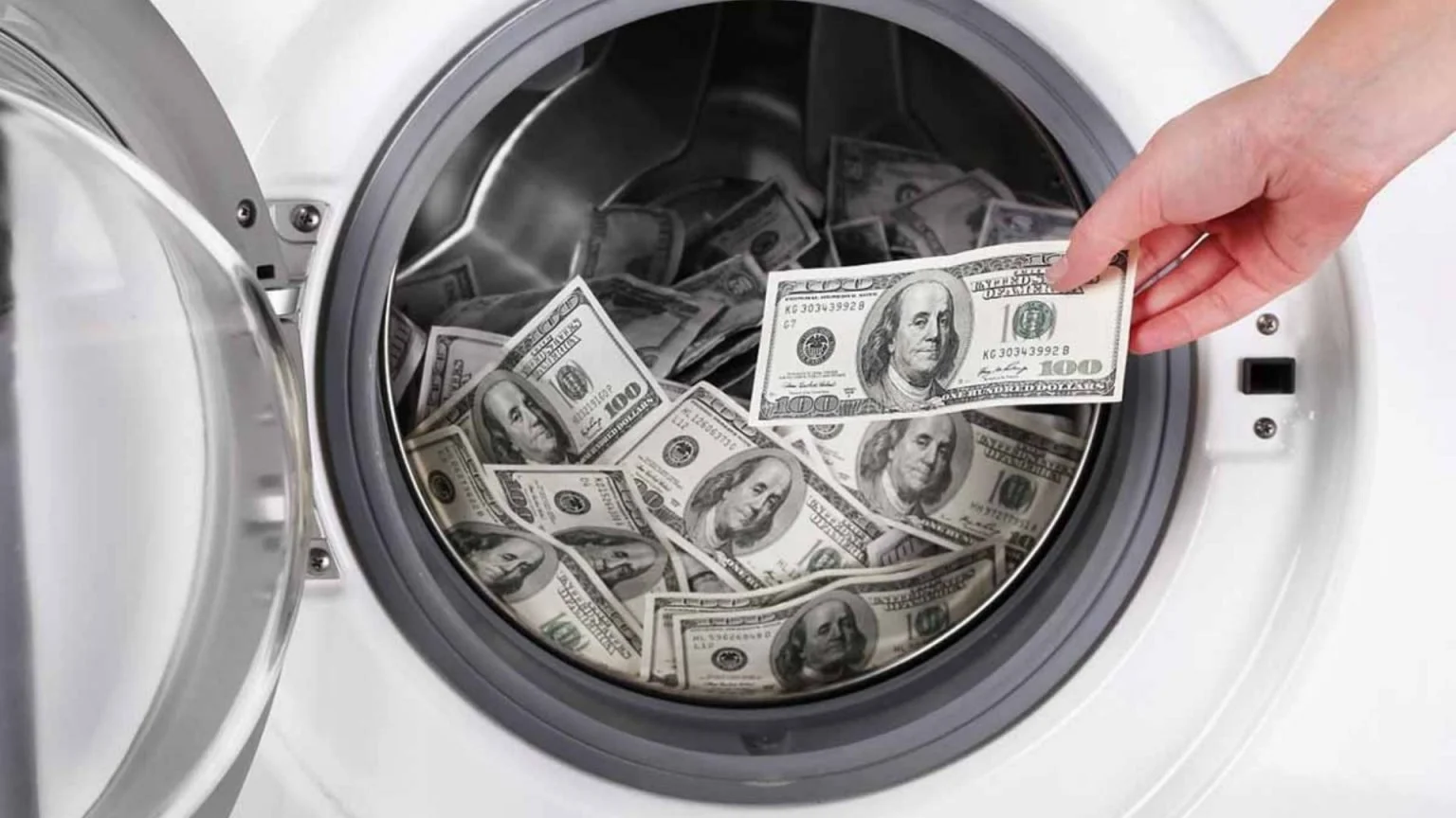 A hand placing a hundred-dollar bill into a washing machine filled with hundred-dollar bills.