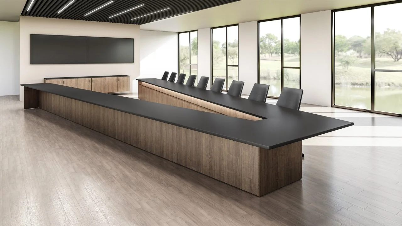 Modern conference room with a long black table, black chairs, large windows with a view of trees and water, and a mounted blackboard.