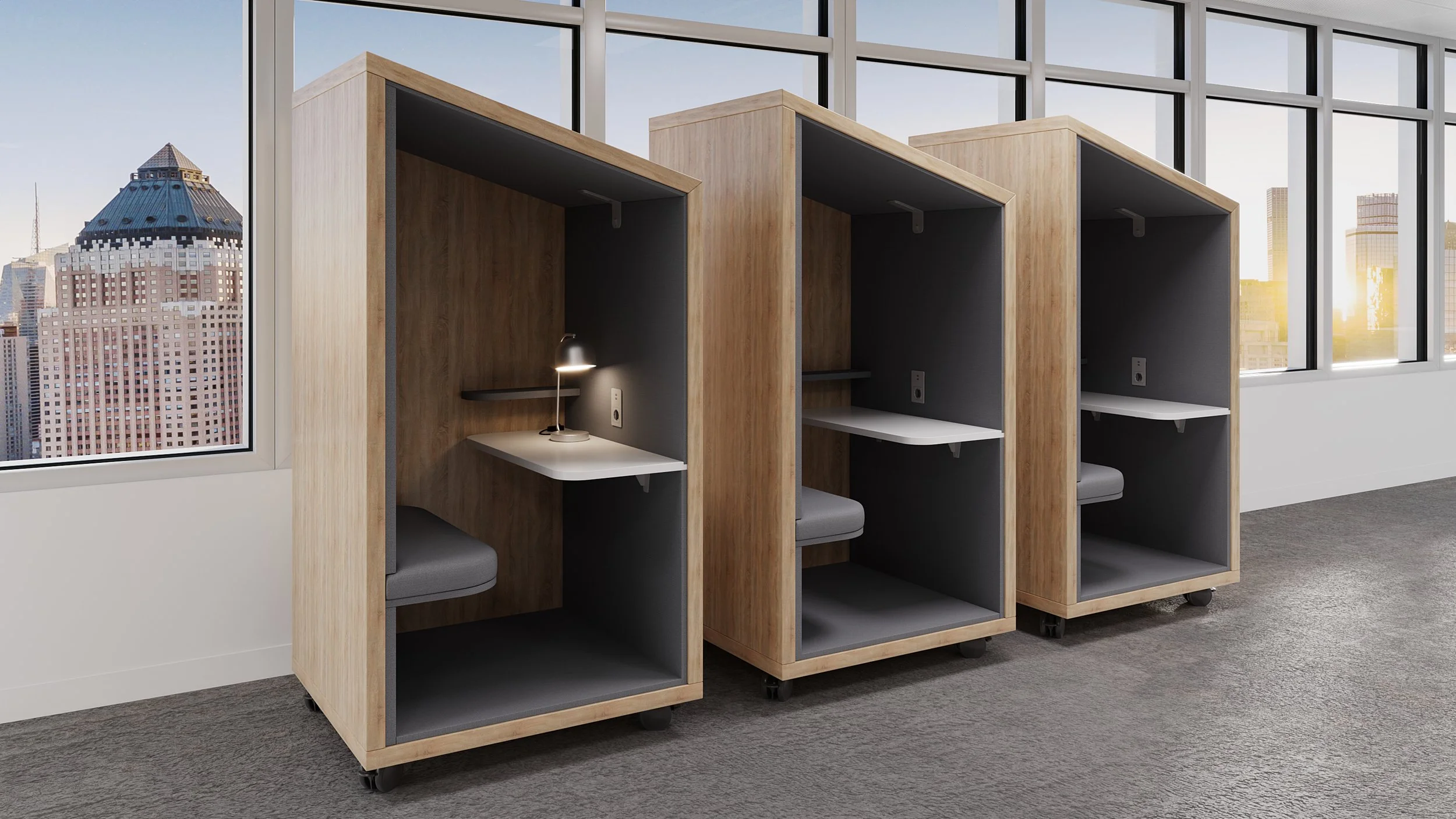 Three wooden privacy pods with built-in desks and cushions, located in an office space with large windows and a city view.