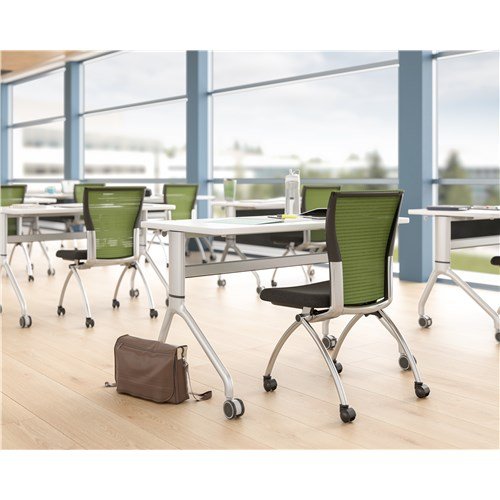 Empty modern classroom with white desks, green chairs, and large windows with a view outside.