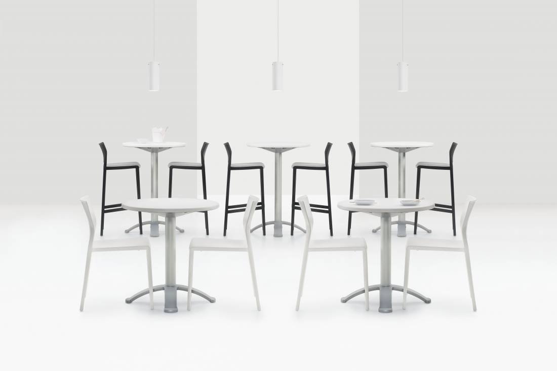 Empty white and black chairs and tables in a minimalist room with white walls and hanging lights.