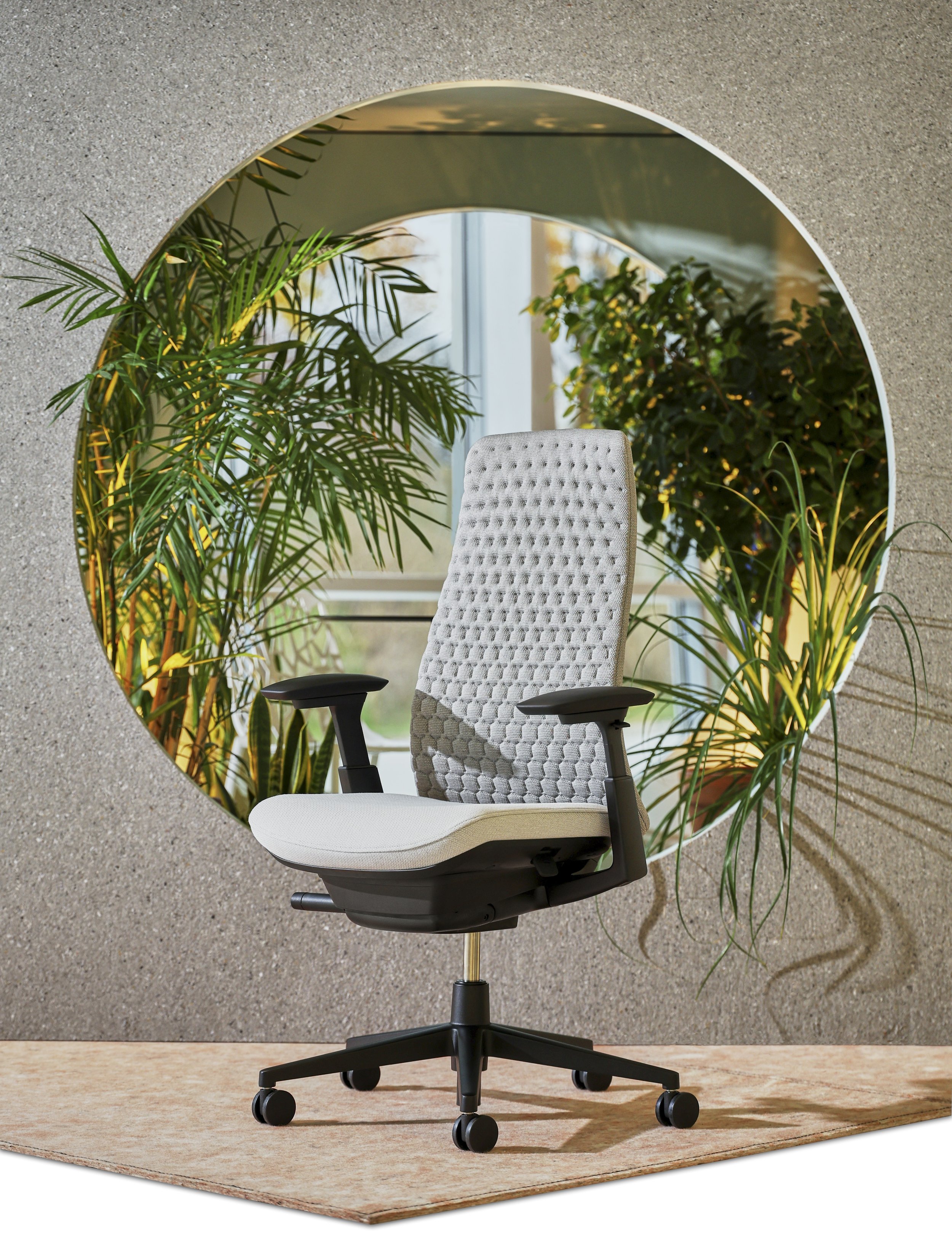 Office chair positioned in front of a circular mirror reflecting indoor plants and a window.