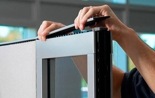Person adjusting or assembling a computer monitor or screen in an office setting.