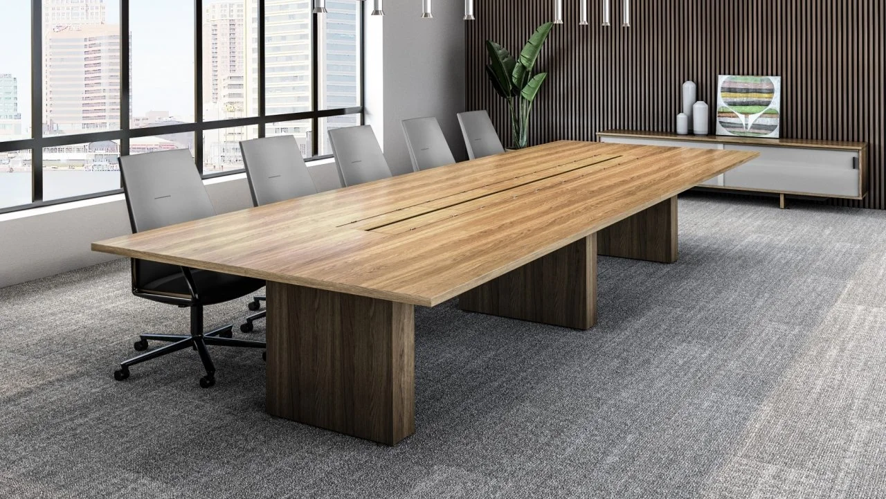 Modern conference room with a long wooden table, six gray chairs, large windows showing city buildings, a potted plant, and decorative vases on a sideboard against a wooden-paneled wall.