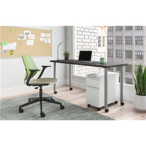 Home office with green and black ergonomic chair, dark desk with laptop, green plant, corkboard with notes, white filing cabinet, and large window with city view.