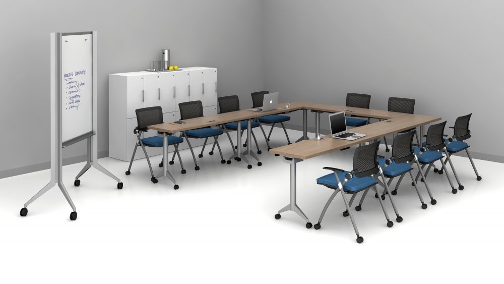 A modern conference room with a U-shaped wooden table, ten blue and black office chairs, two open laptops, a whiteboard on wheels, and a white storage cabinet with a water cooler and glasses on top.