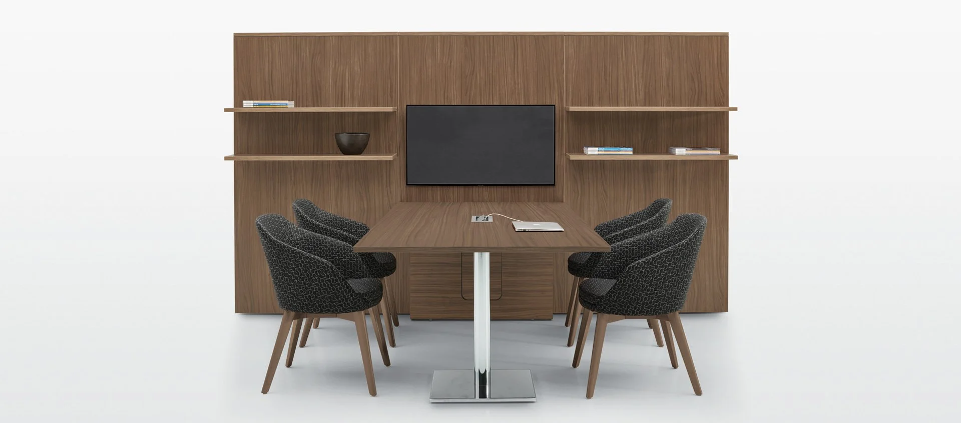 Modern conference room with wooden table, six black patterned chairs, and a wooden wall unit with shelves, a small TV, and minimal decor, set against a white background.
