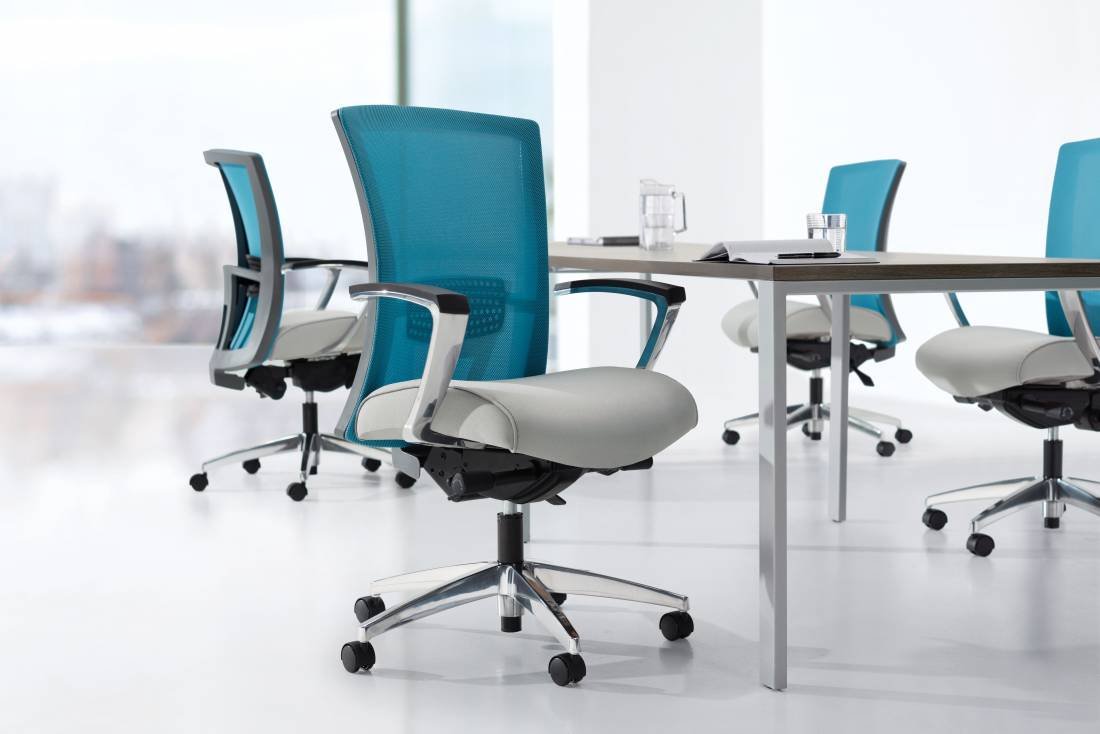 Modern office conference room with blue mesh swivel chairs, a table, and a glass of water on top, against large windows with a city view.