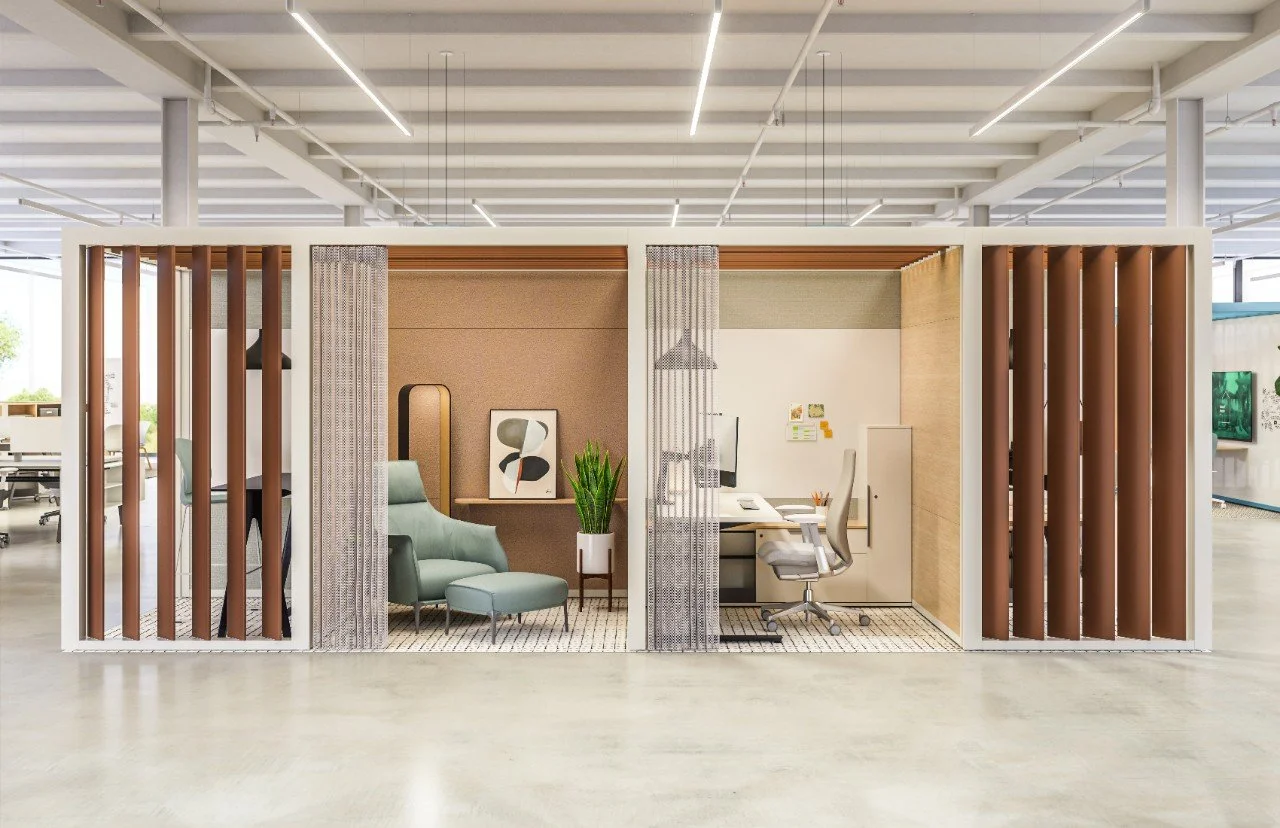 Modern office cubicle with a seating area, desk, and ergonomic chair, enclosed by decorative slatted panels in a corporate workspace.