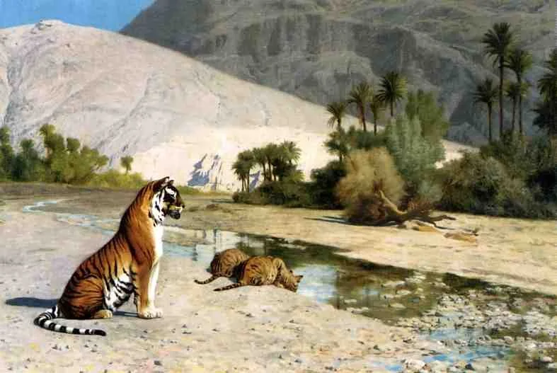A tiger sitting near a water stream with two tiger cubs drinking water, surrounded by desert landscape, sparse trees, and mountains in the background.