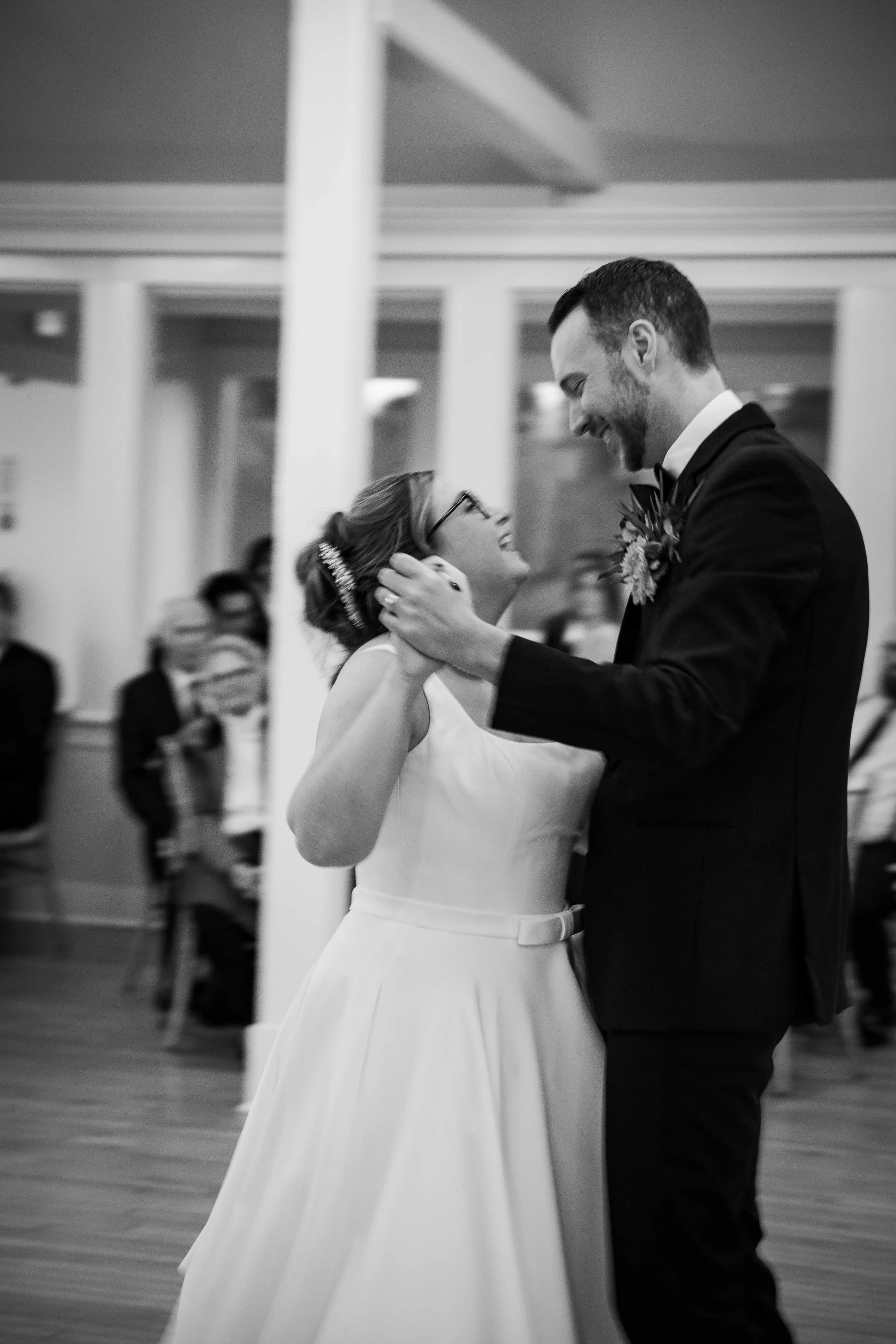 A bride and groom sharing their first dance at their wedding reception, smiling and looking into each other's eyes.