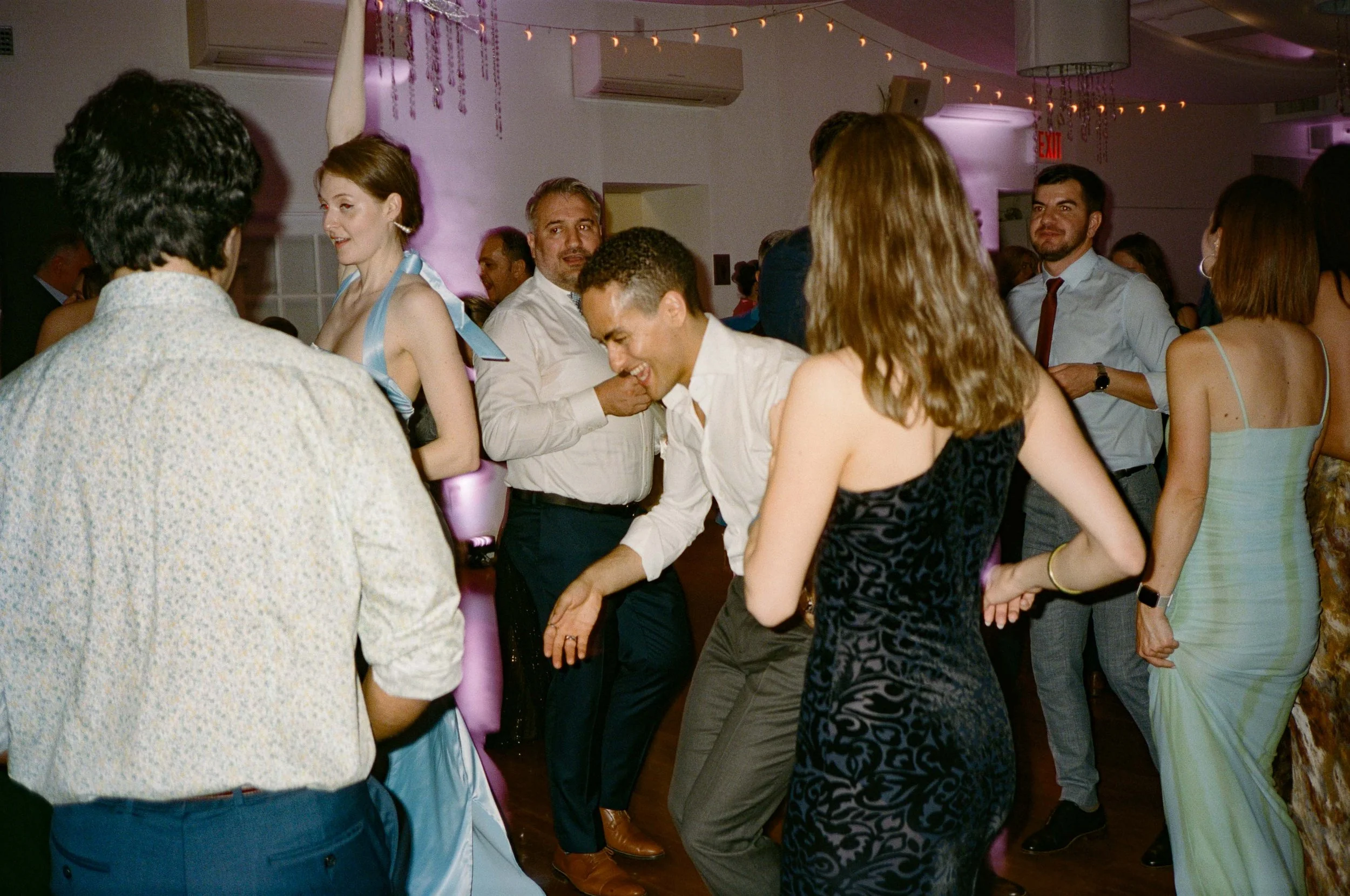 People dancing and enjoying themselves at a party or celebration with purple lighting and decorations.