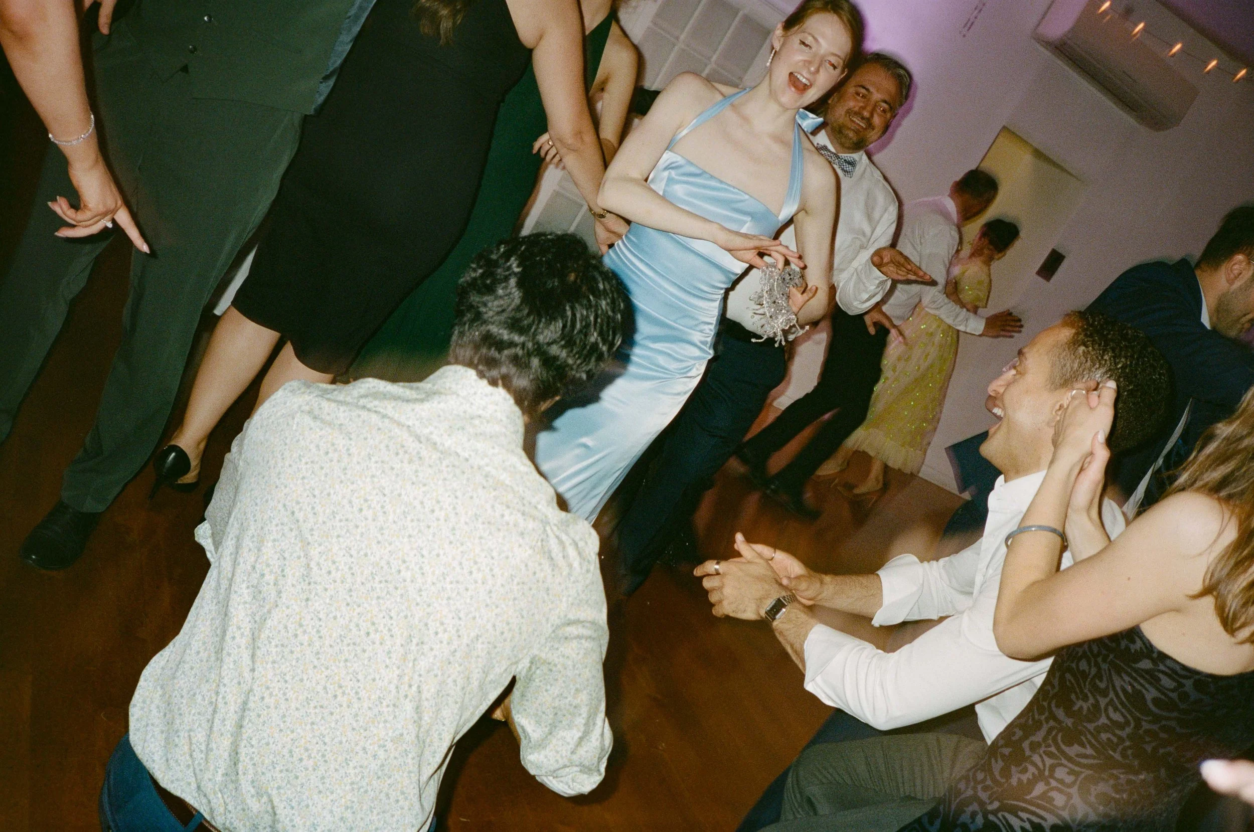 People dancing and socializing at a party or celebration, with some holding drinks and chatting.