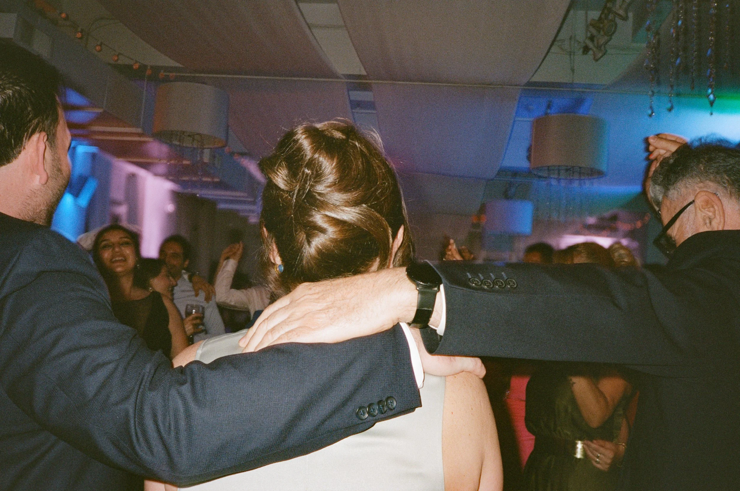People dancing at a party with colorful lighting.