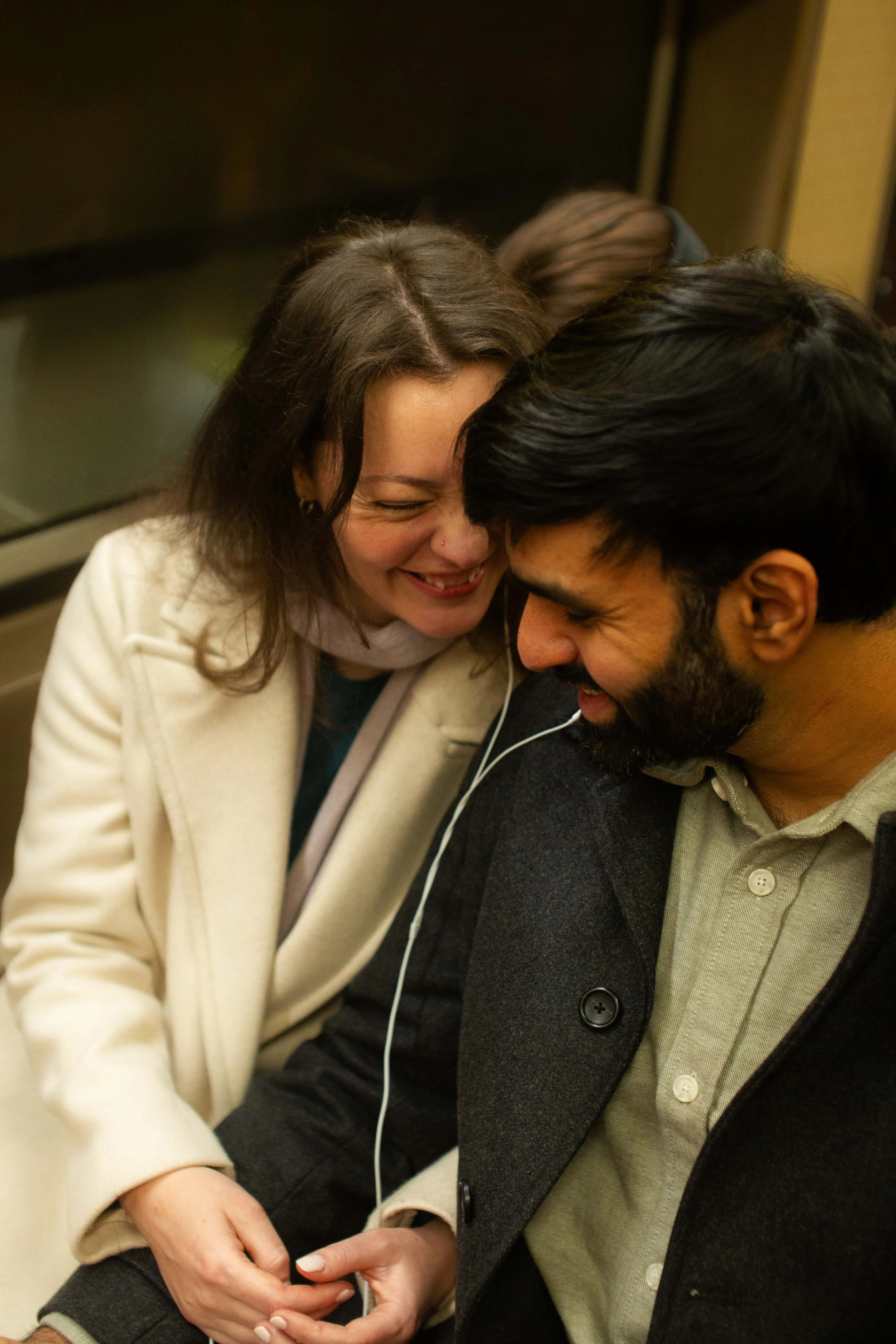 A woman and a man are sharing an intimate moment, with their foreheads touching and eyes closed, smiling and appearing happy.
