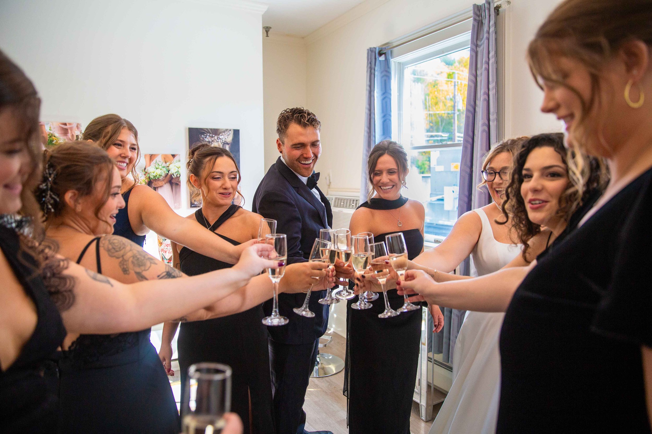Group of people celebrating with champagne in a home, dressed in formal attire, smiling and toasting.