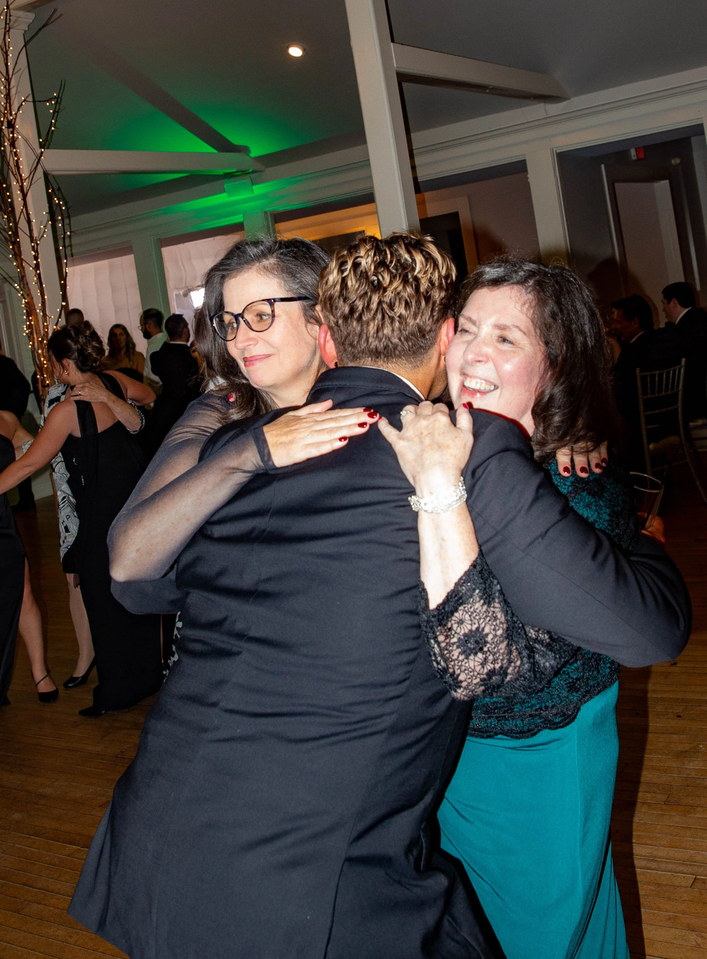 People hugging and celebrating at a formal event or party.