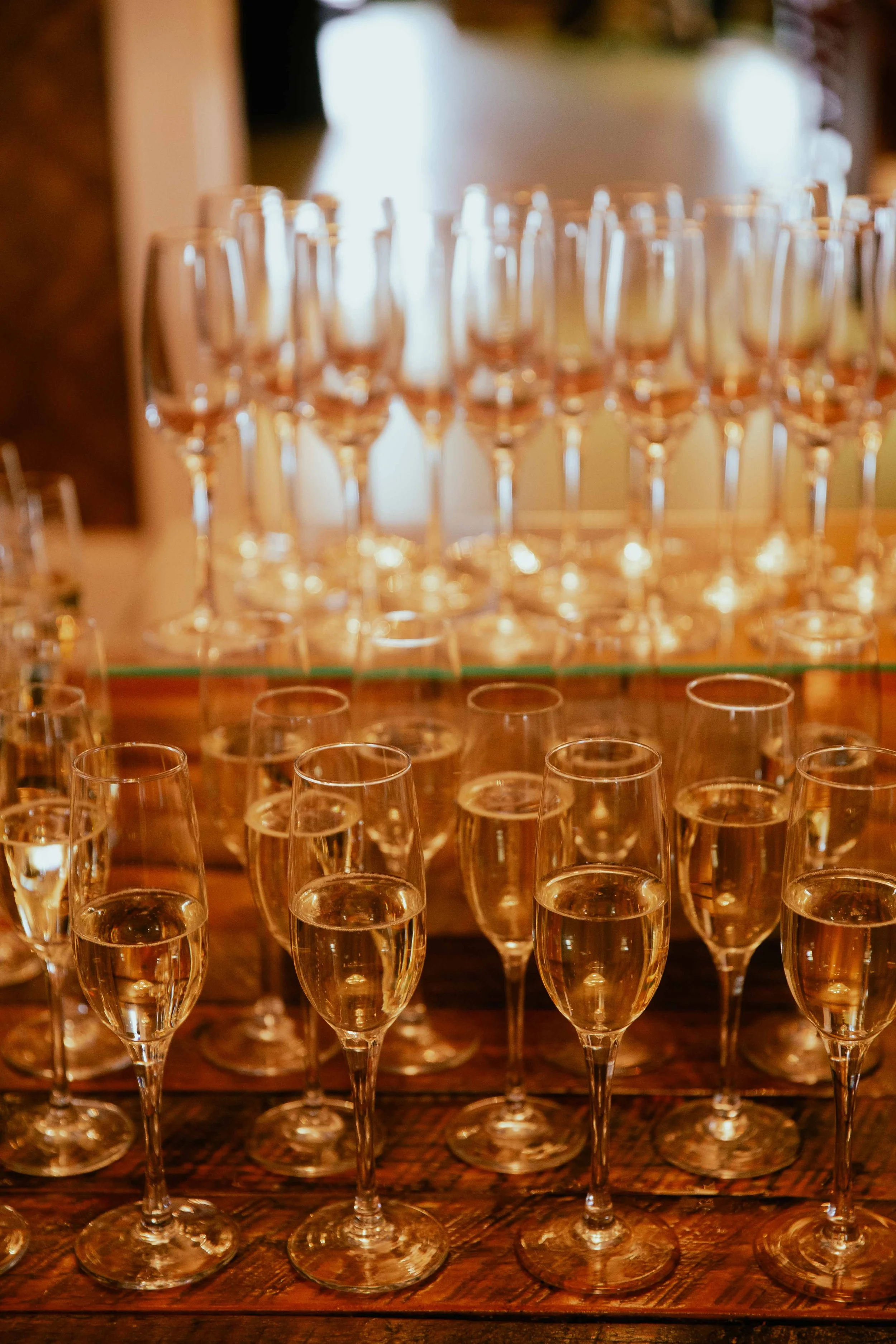 Multiple glasses of champagne arranged on a wooden table, with some filled and some empty.