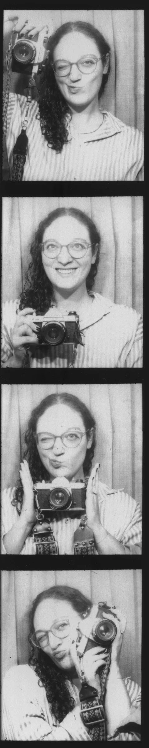 A woman with glasses, long curly hair, and wearing a striped shirt taking selfies with a camera in four different poses against a curtain background.