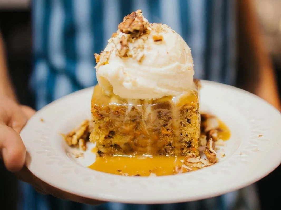 Slice of cake topped with a scoop of vanilla ice cream and caramel sauce