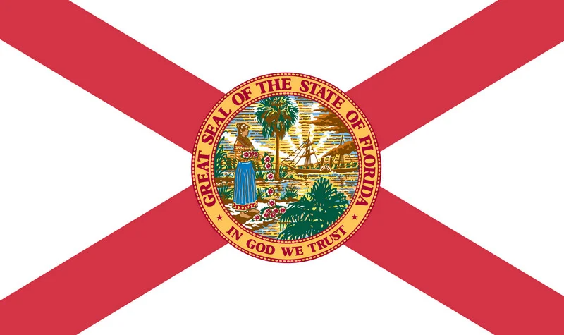 The Florida state flag with a red diagonal cross and the state seal in the center, featuring a Native American woman, a palm tree, and a sailing ship.