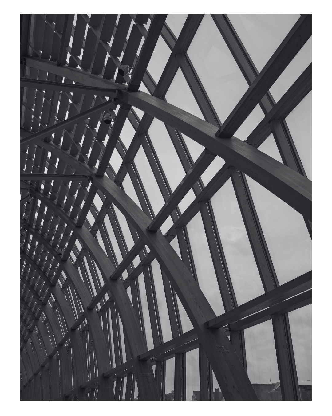 Interior view of a modern architectural structure with intersecting wooden beams and large glass windows.