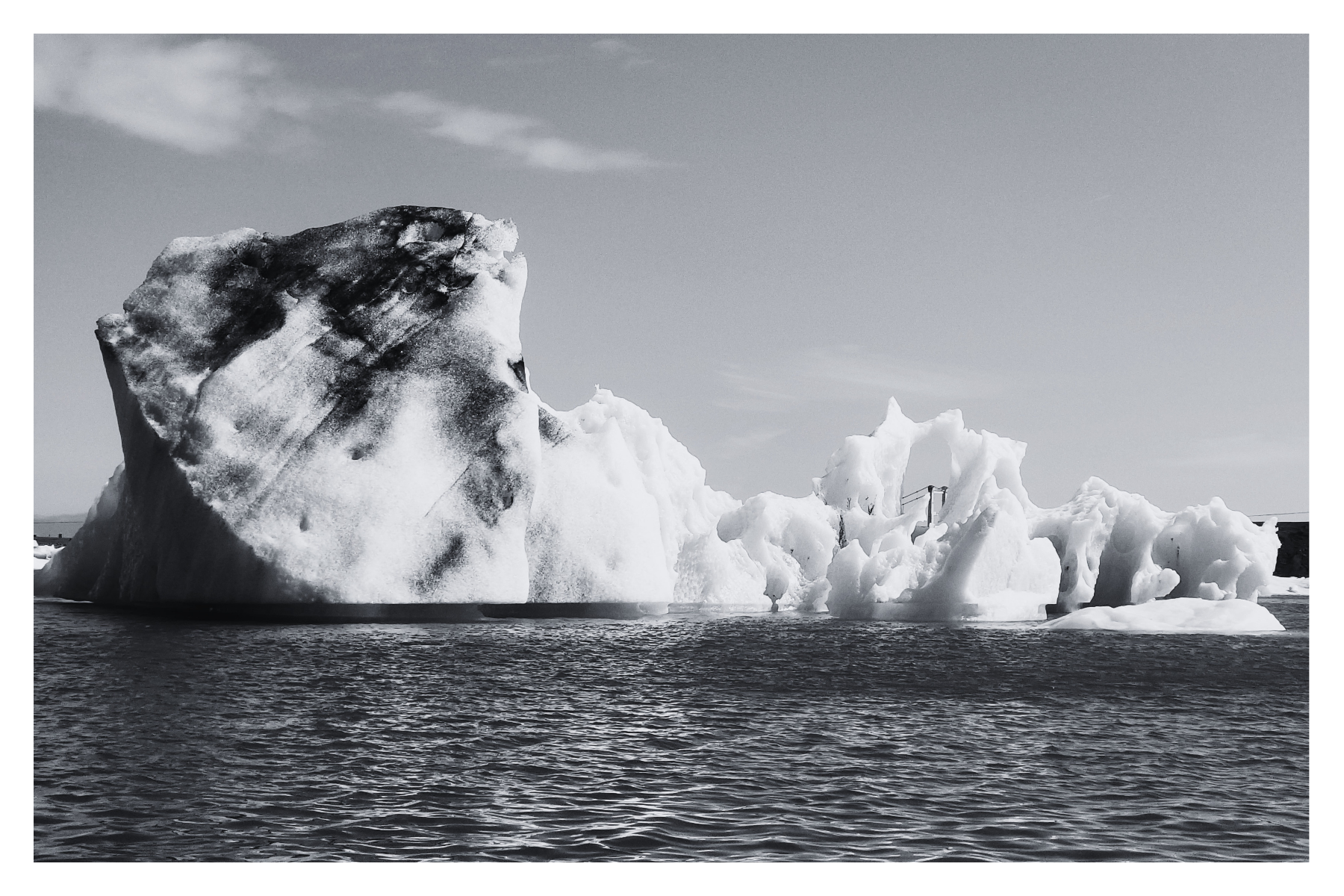 A large iceberg floating in the ocean with a clear sky above.
