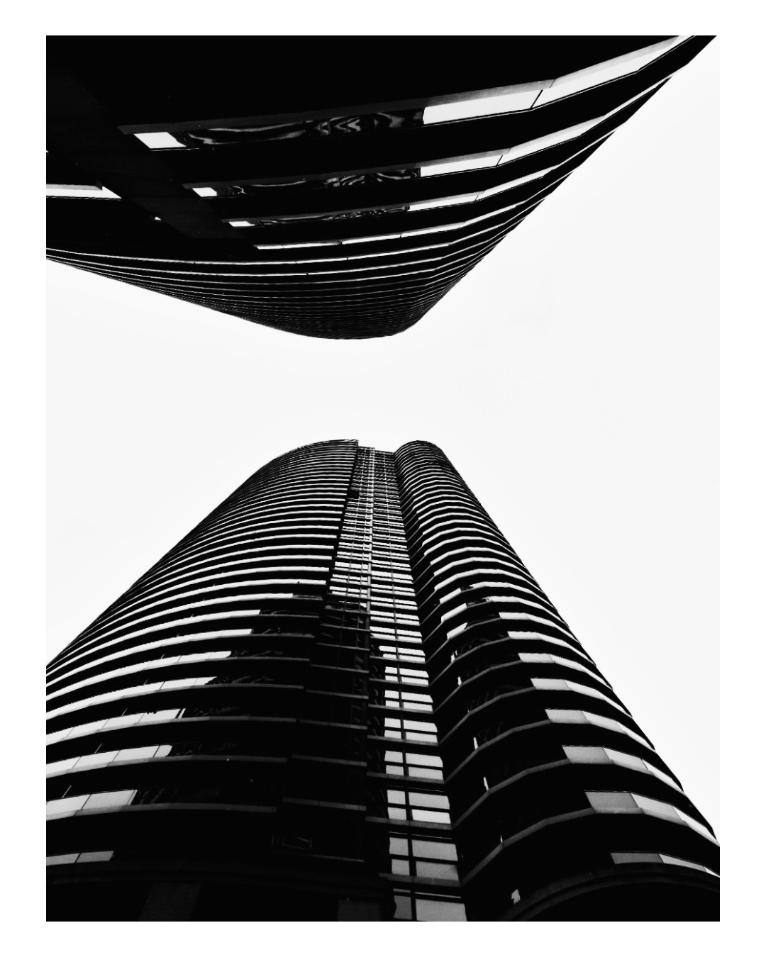 Low-angle black and white photograph of two modern high-rise buildings with curved, horizontal lines, viewed from the ground looking up.