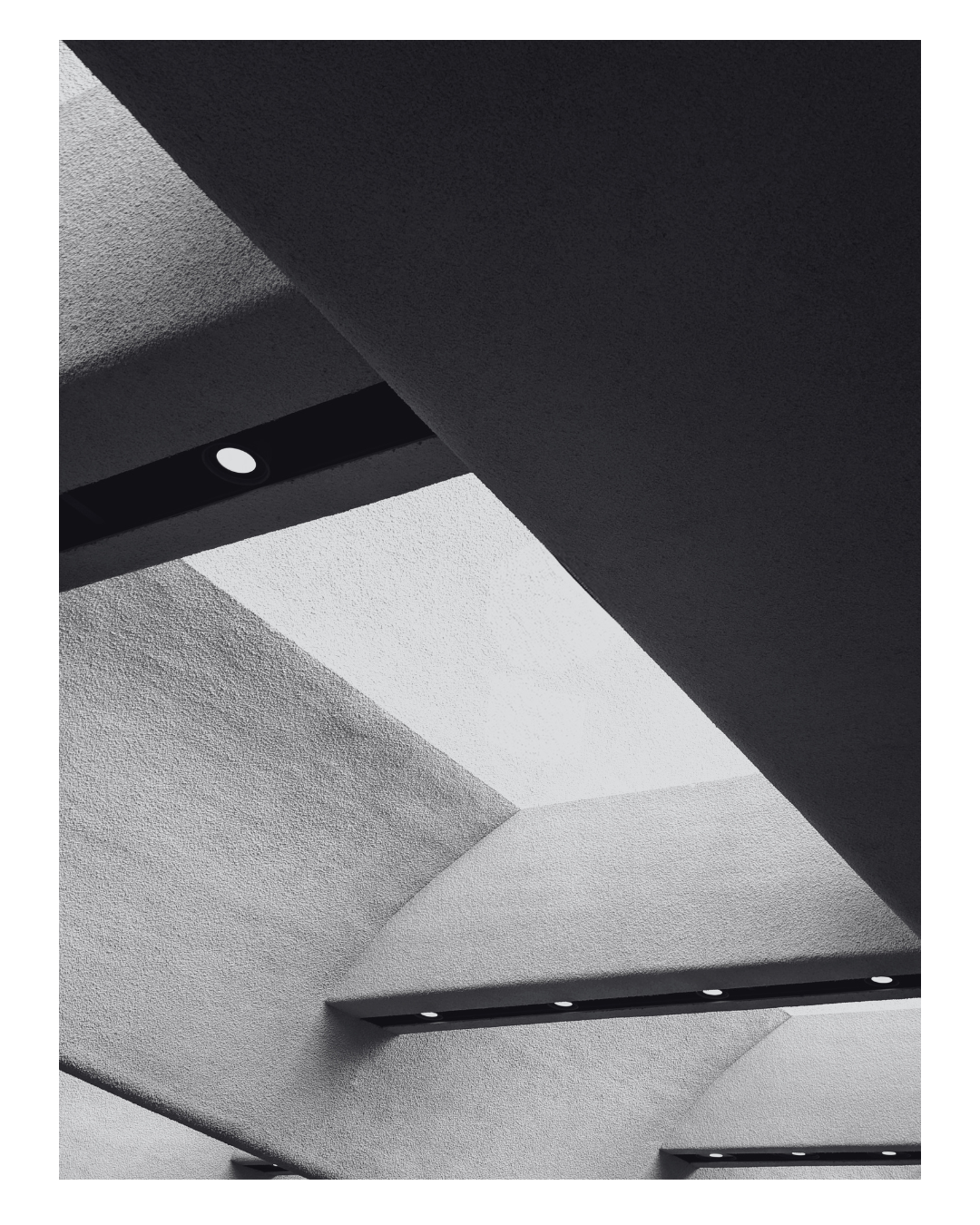 Ceiling with textured white and gray surfaces and embedded circular ceiling lights.